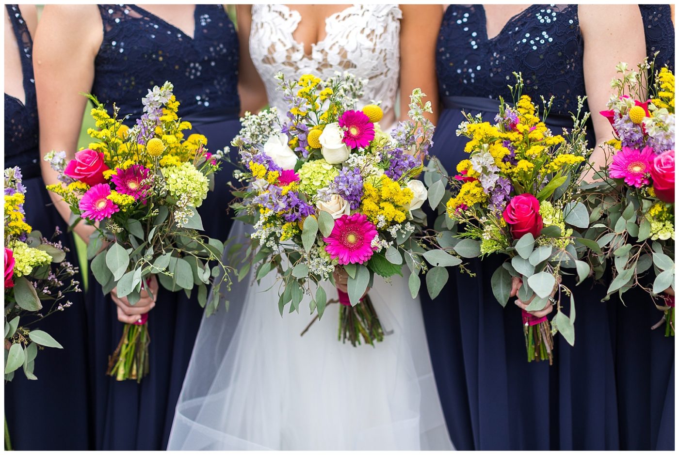 Bridesmaids standing while holding their flower bouquets against their dresses