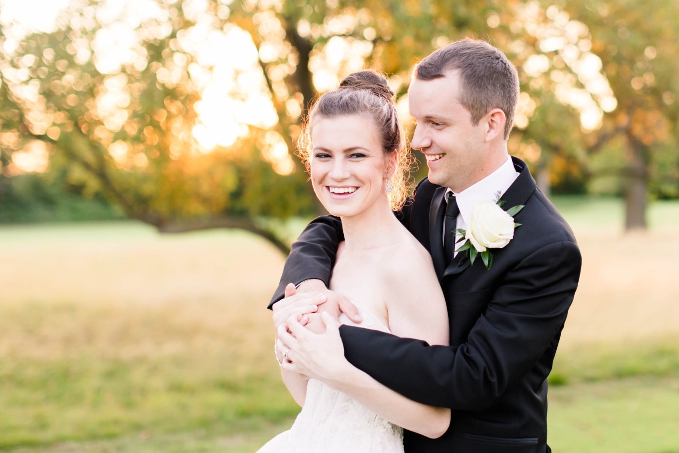Bride joyfully laughing with her groom on her wedding day in a field of tall grass in Indiana 