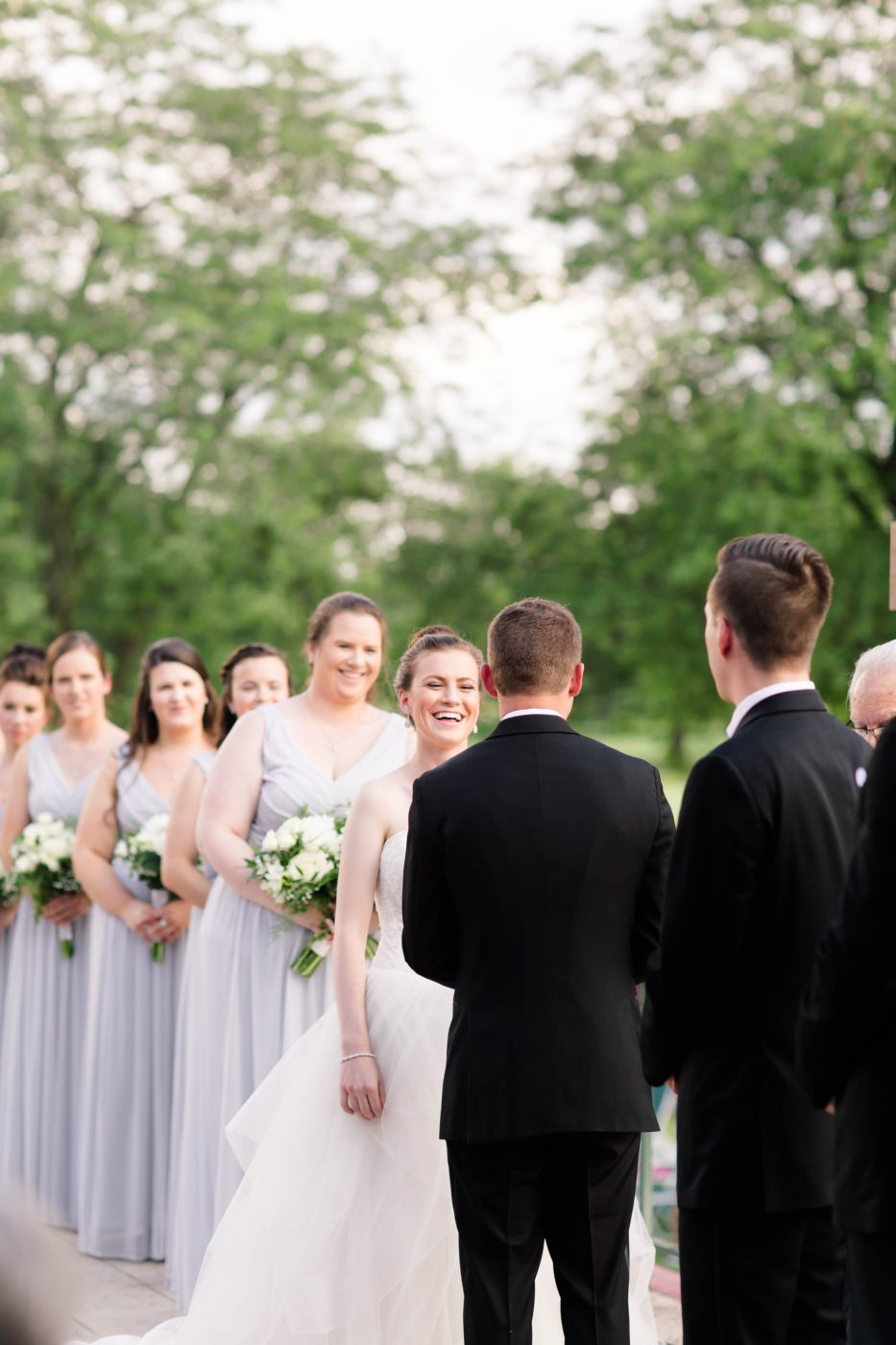 Bride laughing while looking at her groom while they are giving their vows during their ceremony 