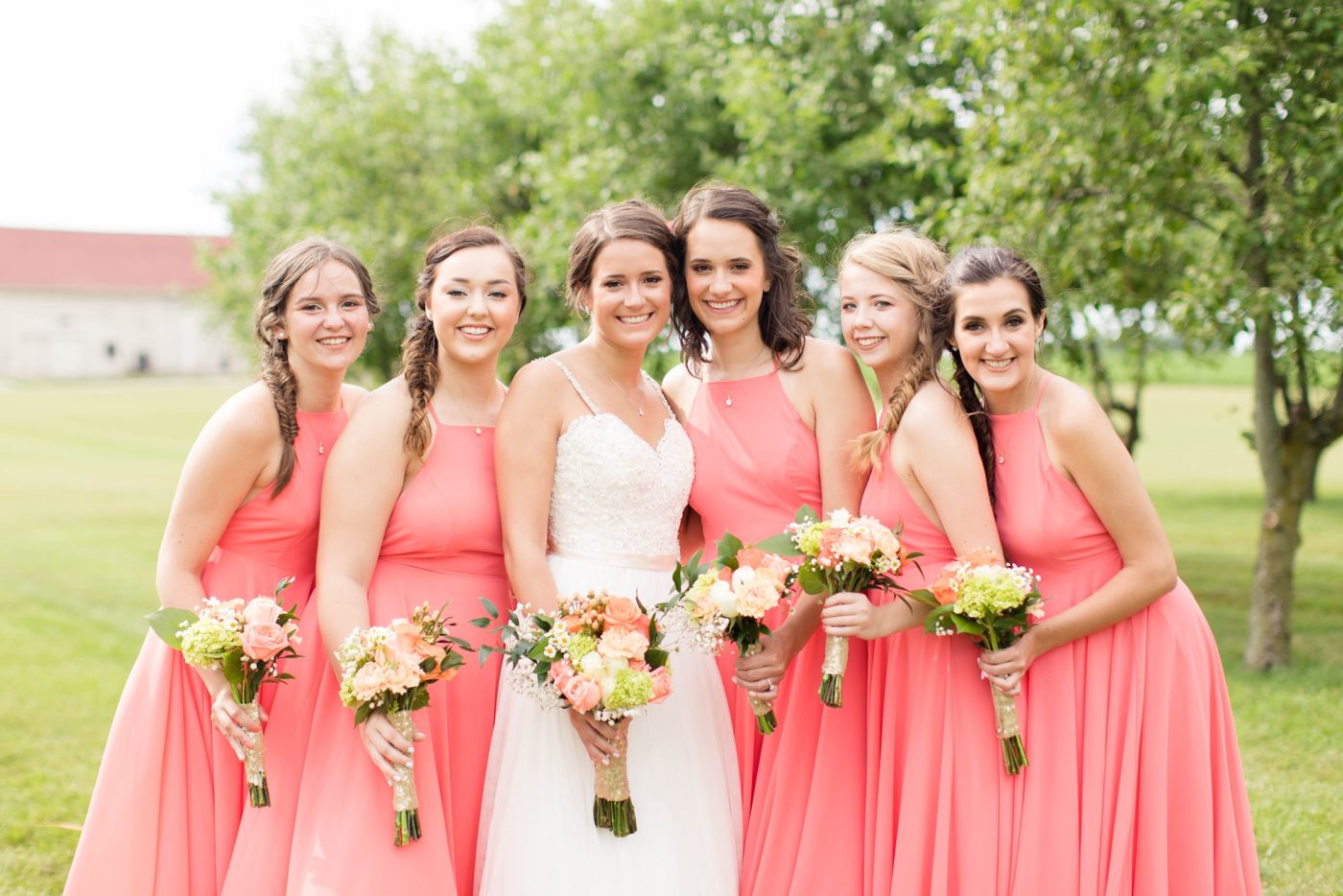 Bridesmaids smiling and looking at the camera in color bright dresses at a wedding. 