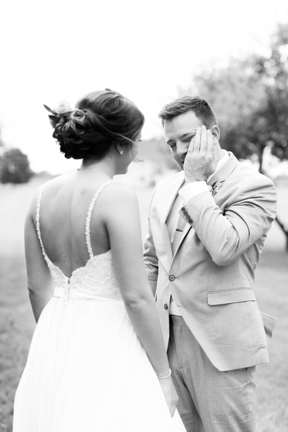 Groom in tears after seeing his bride for the first time. Groom wiping away tears from his face. 