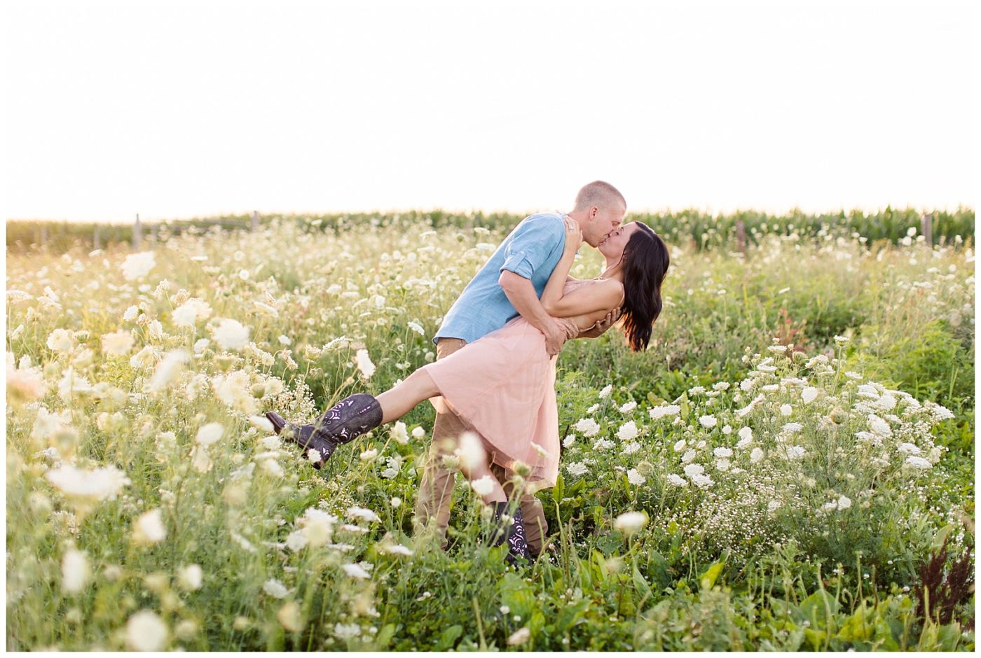 Engaged couple dipping and kissing in a field of wildflowers for their photos 