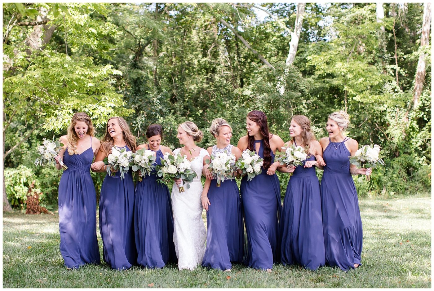 Bridesmaids linking arms and walking together while laughing and having fun together